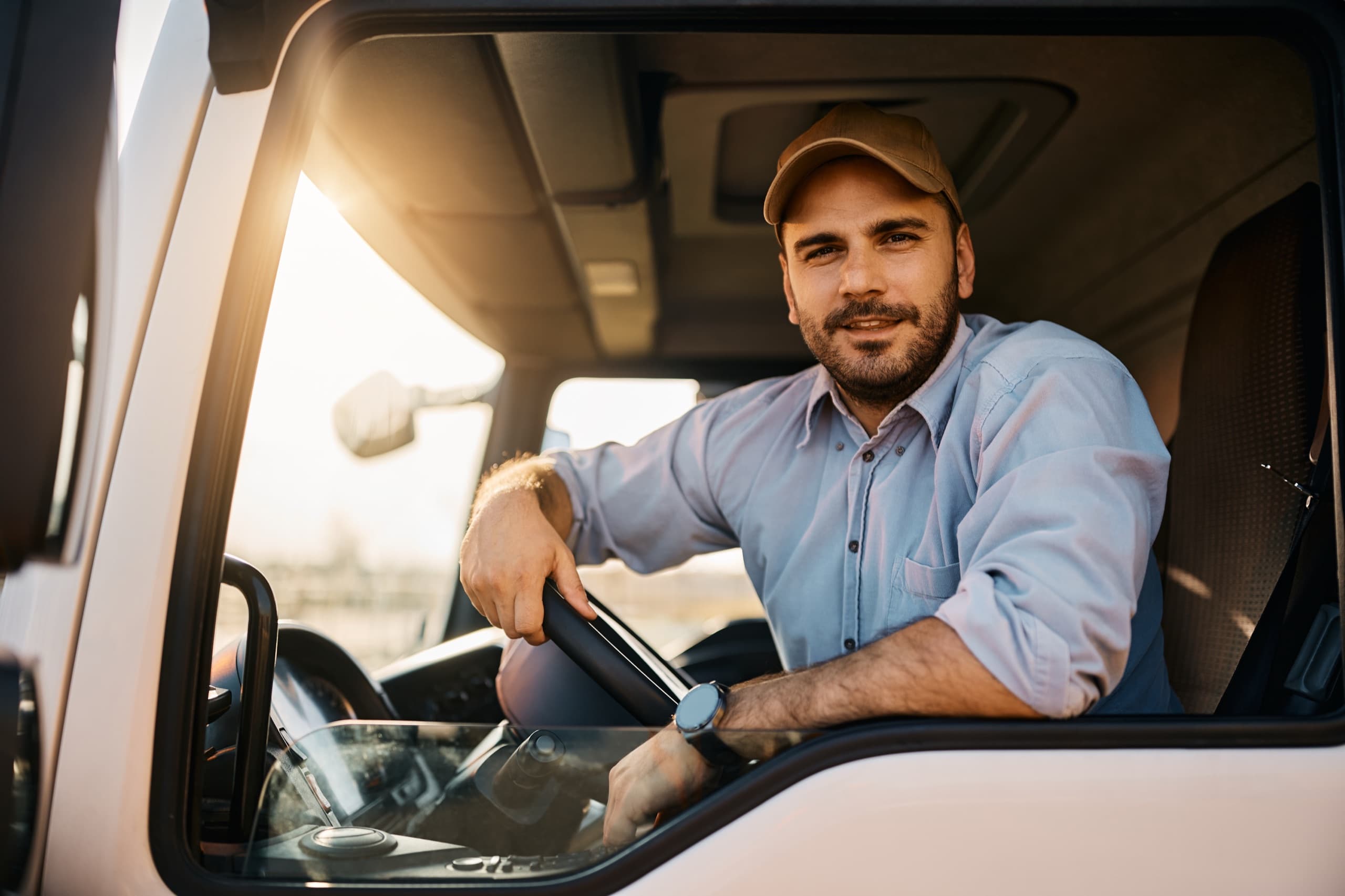 A smiling truck driver at the wheel of his cab